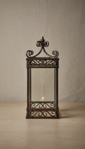 Handcrafted forged iron scrollwork lantern with clear glass panels and decorative finial top