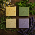 Taureanlace Handmade Soap in four botanical varieties — chamomile, mint, rosemary, and lavender — with botanical stamp detail